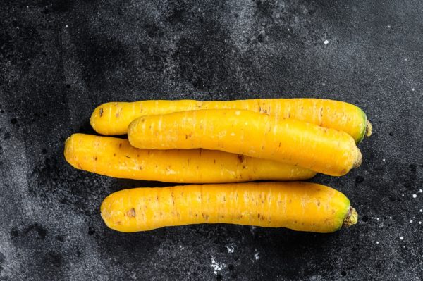Yellow organic carrots without tops. Black background. Top view
